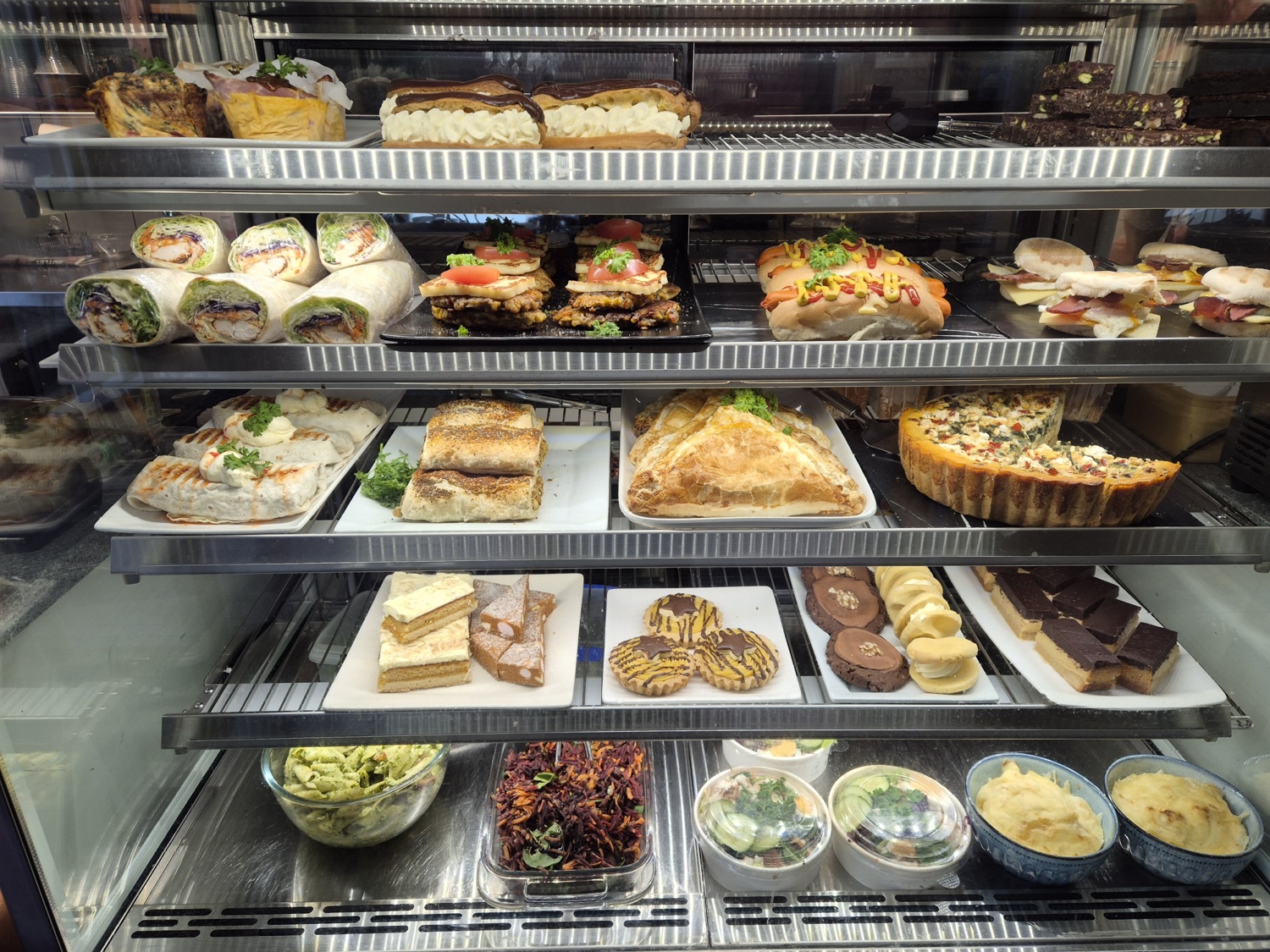 The cabinet stocked with sandwiches, quiches, salads and slices
