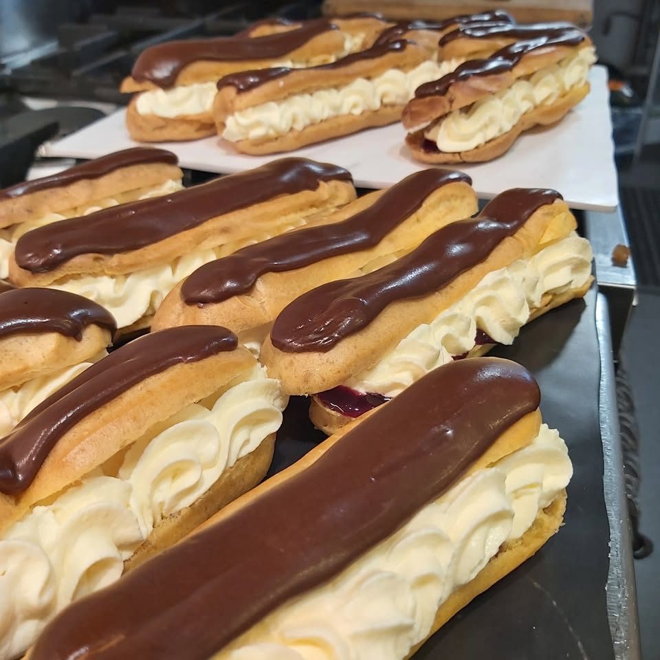 A tray of chocolate eclairs filled with cream